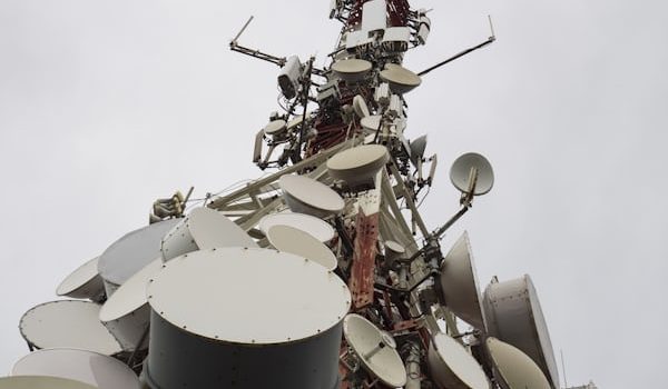 Telecom tower with microwave dish antennas against grey sky